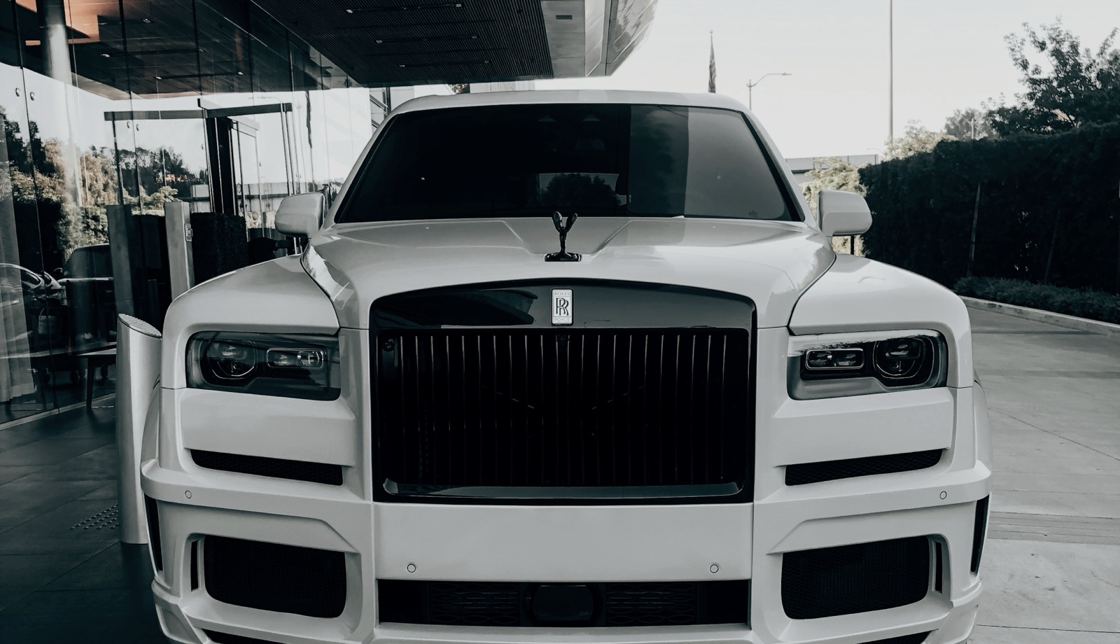 A white Rolls-Royce Cullinan photographed head on, its paint catching the light.