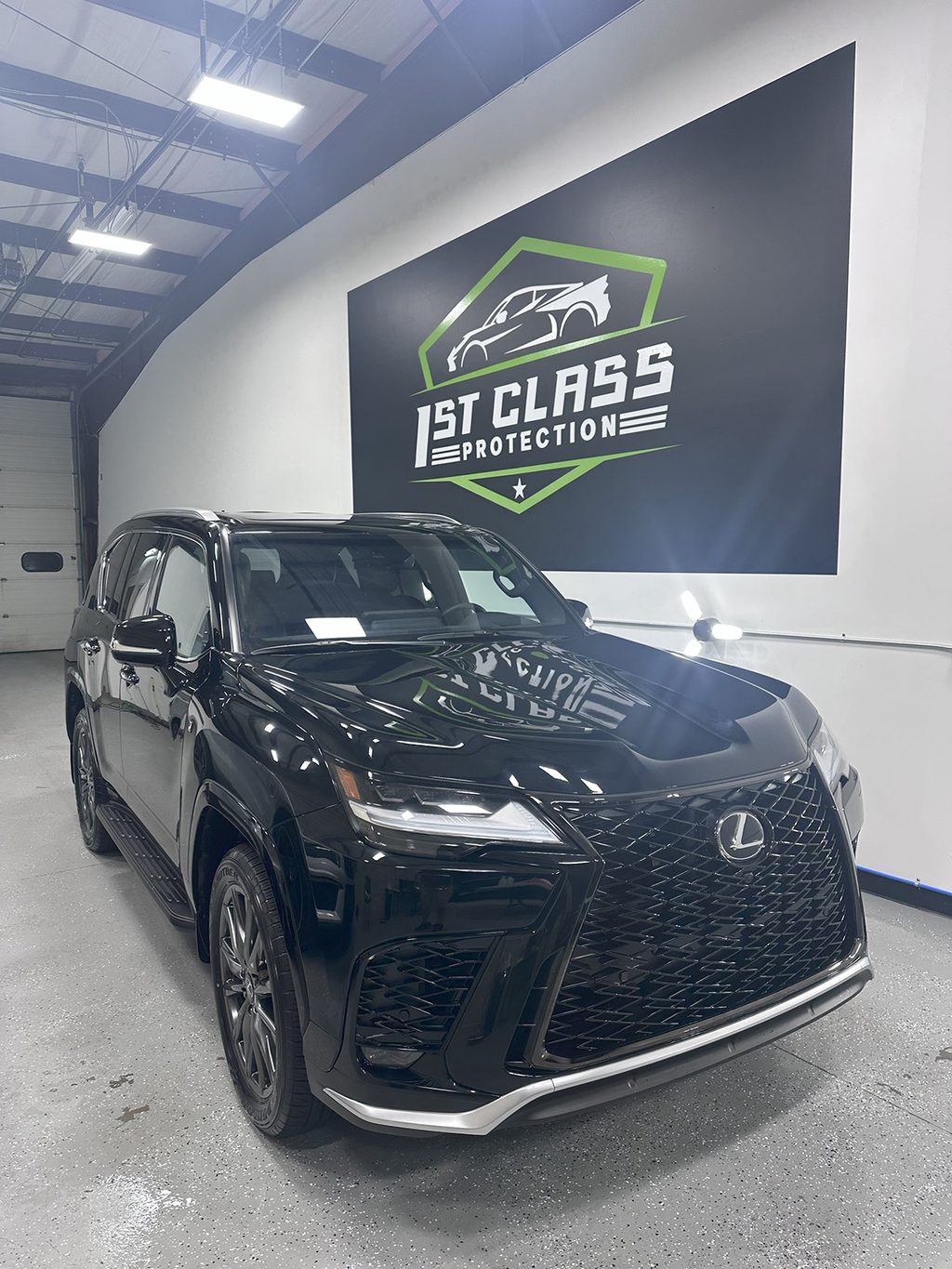 A black Lexus LX reflecting the shop wall sign in its hood after correction and coating.