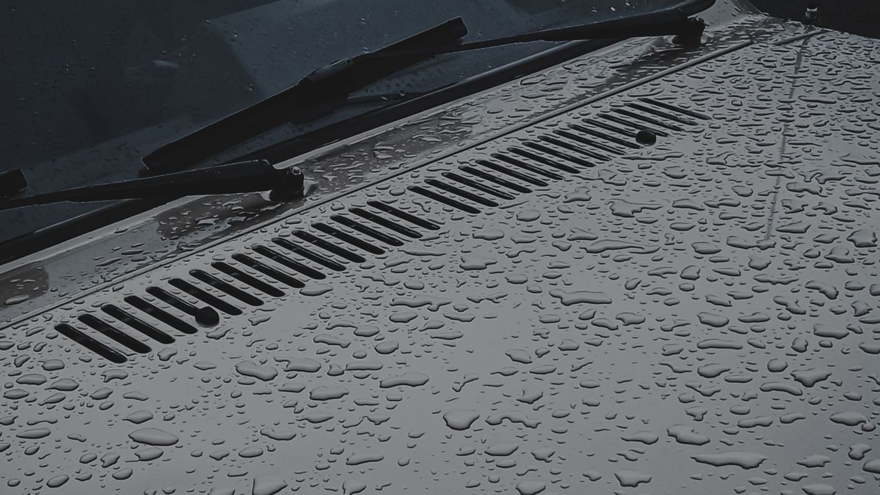 Water beading tightly on a dark painted panel.